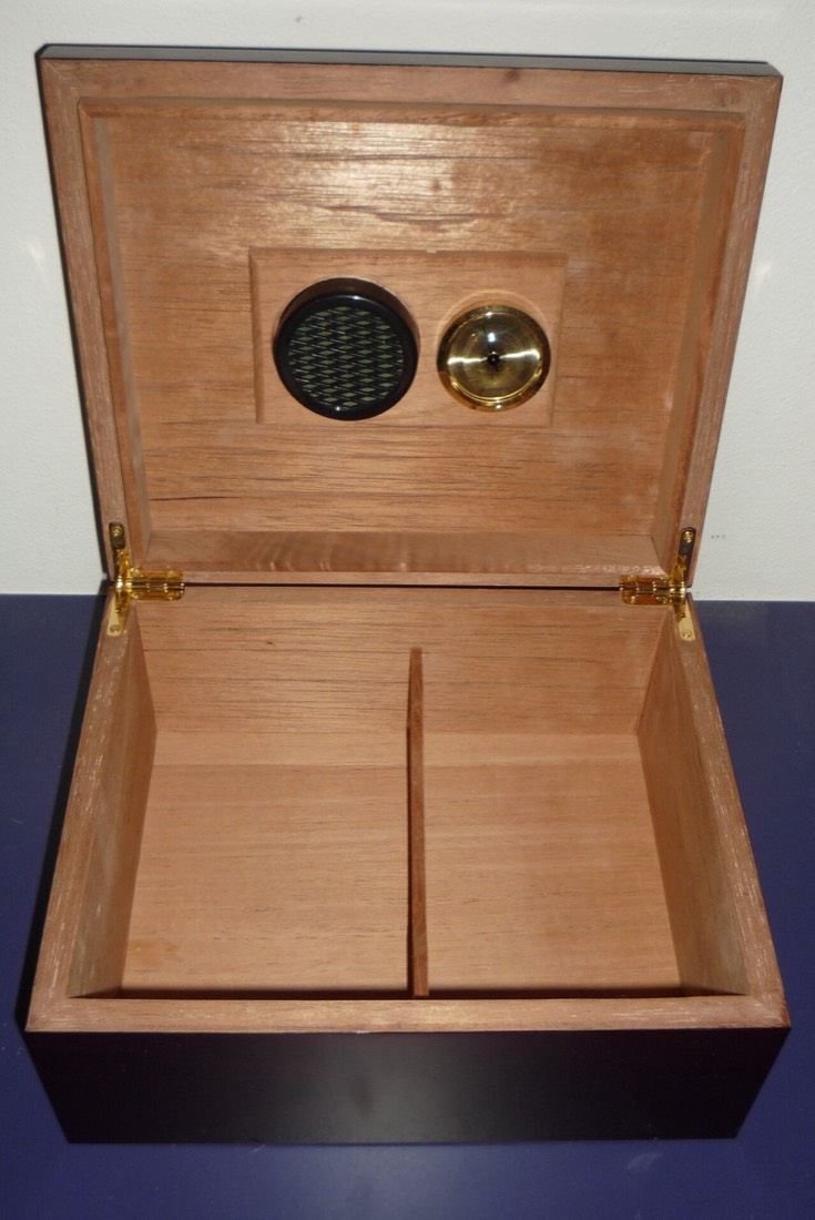 An open humidor holding cigars with a round hygrometer gauge